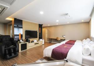 a hotel room with a bed and a flat screen tv at No.1 New Yorker Hotel in Jinju