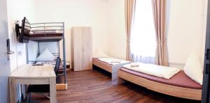 een kamer met 2 stapelbedden en een bureau bij FMM Hostel in Memmingen