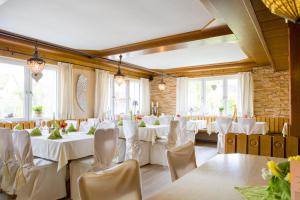 un salón de banquetes con mesas y sillas blancas en Landhaus Engel, en Erlaheim