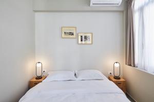 ein Schlafzimmer mit einem weißen Bett mit zwei Lampen in der Unterkunft Be based near Acropolis, in an exquisite studio! in Athen