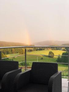 a balcony with two chairs and a view of a field at Willa Hańcza in Smolniki