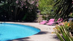 a swimming pool with two lounge chairs and flowers at Gite de l'Amandari - classé 3 etoiles Prefecture - piscine chauffée privative, terrasses et jardin, 5 minutes à pied du village in Plan-de-la-Tour +19 photos