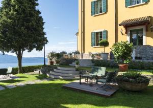 une maison avec une table et des chaises dans la cour dans l'établissement Boutique Hotel Villa Sostaga, à Gargnano
