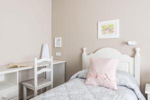 a bedroom with a white bed with a pink pillow at Hostal Buenos Aires in Tremp