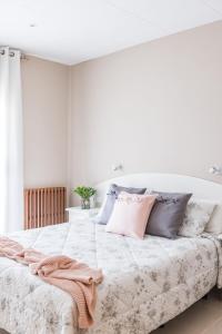 een witte slaapkamer met een groot bed met roze en grijze kussens bij Hostal Buenos Aires in Tremp