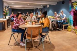 un grupo de personas sentadas en mesas en un restaurante en Stayokay Hostel Amsterdam Oost, en Ámsterdam