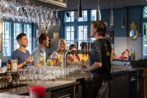 eine Gruppe von Leuten, die in einer Bar mit einem Barkeeper stehen in der Unterkunft Stayokay Hostel Amsterdam Oost in Amsterdam