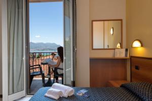 a woman sitting on a bed in a hotel room at Hotel Boston in Stresa
