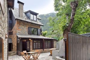 a stone house with a table and a fence at Luderna - Casa con terraza dera Aubeta in Garós