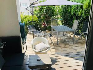 une terrasse avec des chaises, une table et un parasol dans l'établissement 25h GARDEN Apartment PLUS private Beach, à Neusiedl am See