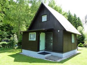 uma pequena casa preta com uma porta verde em Chaty Vysočina em Polesí