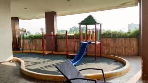 a playground with a slide and chairs on a patio at Cozy Studio Serpong Greenview Apartment By Travelio in Ciater-hilir