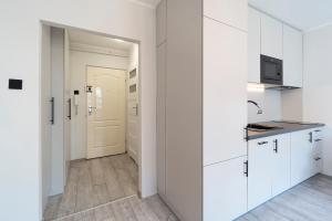 a white kitchen with white cabinets and a door at IV apart in Gdynia