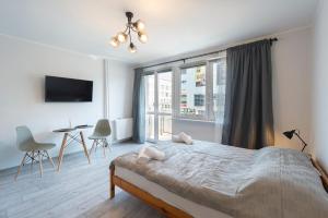 a bedroom with a bed and a table and a window at 4 Apart in Gdynia