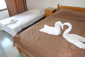 dois cisnes feitos de toalhas sentadas numa cama em КЪЩА"Перла" em Ravda