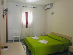 a room with a green bed and a window at Albergo Villamarina in Santa Teresa Gallura +9 photos