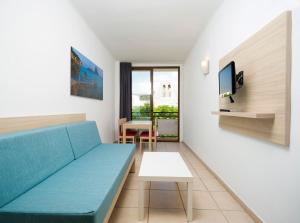 a living room with a blue couch and a table at Apartamentos Tramuntana in San Antonio