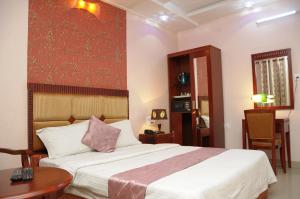 a bedroom with a large bed and a table at Hotel Kings Kastle in Mysore