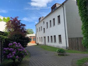 ein weißes Gebäude mit lila Blumen davor in der Unterkunft Hinterhaus Apartment No1 in Leipzig