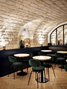 restauracja ze stołami i krzesłami oraz kamienną ścianą w obiekcie Hotel Rendez-Vous Batignolles w Paryżu