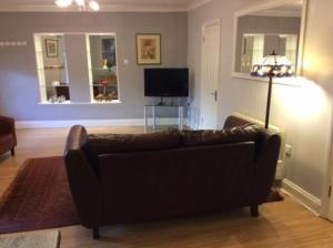 uma sala de estar com um sofá de couro e uma televisão em Stansted spacious 2-bed apartment, easy access to Stansted Airport & London em Stansted Mountfitchet