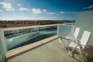 een balkon met 2 stoelen en uitzicht op het strand bij Hotel Boutique TAO Caleta Mar in Corralejo