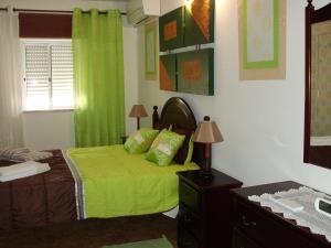 a bedroom with a bed with green sheets and a window at Moradia perto dos Palmares in Lagos