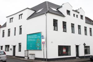 un bâtiment blanc avec un panneau devant lui dans l'établissement Work & Stay in Kleve IIII, à Clèves