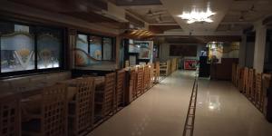 a room filled with rows of tables and chairs at Hotel Mahendra in Jālgaon