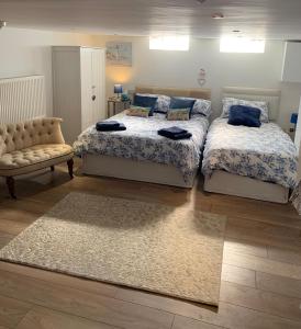a bedroom with two beds and a couch and a rug at Whitby Wave breaker studio in Whitby