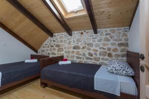 a bedroom with two beds and a stone wall at Kuća za odmor Joko i Jeka in Bogatić +58 photos