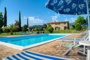 a pool with chairs and an umbrella in front of a house at Agriturismo Le Terre del Casale in Assisi