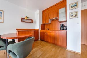 a kitchen with wooden cabinets and a table and chairs at Apartamenty Sun & Snow w Rezydencji Bielik in Międzyzdroje