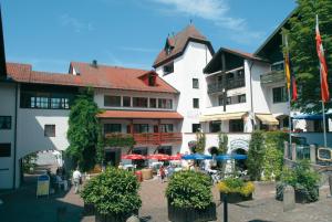 ein Gebäude mit Tischen und Sonnenschirmen im Innenhof in der Unterkunft Appartement-Haus Blumenhof in Bad Griesbach