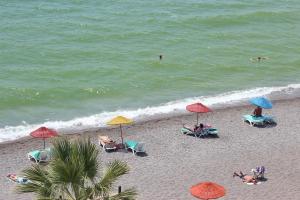 ein Strand mit Stühlen und Sonnenschirmen und Menschen am Strand in der Unterkunft Hotel Berlin in Fethiye