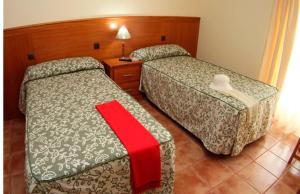 Dos camas en una habitación de hotel con un color rojo en Nuevo Hostal Paulino, en Trujillo