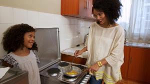 Uma mulher e uma rapariga numa cozinha a preparar comida. em Victoria Guesthouse Addis em Addis Ababa