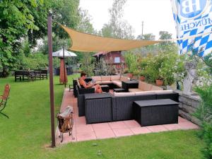 une femme assise sur un patio sous un auvent dans l'établissement Landhotel Römerkessel, à Landsberg am Lech