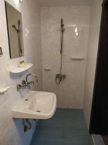 a white bathroom with a sink and a shower at Dedovite Kashti in Stefanovo