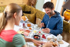 Ein Mann und eine Frau sitzen am Tisch und essen Frühstück. in der Unterkunft Hotel Seppl in Innsbruck