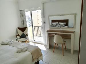 una camera con letto, scrivania e specchio di Acropole Algarve Beach Apartment a Portimão