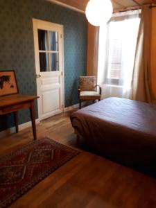 a bedroom with a bed and a table and a window at La maison des archers in Saint-Saturnin