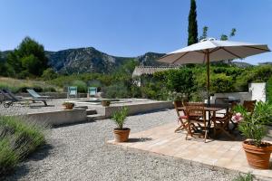eine Terrasse mit einem Sonnenschirm, einem Tisch und Stühlen in der Unterkunft Le Mas des Genets in Saint-Rémy-de-Provence