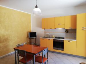 ヴィニャカストリジにあるCasa Vacanze Rosalbaのキッチン(黄色のキャビネット、テーブル、椅子付)