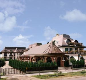 a large building with a roof with a fence at Karikas Hotel in Hajdúszoboszló