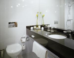 a bathroom with a sink and a toilet and a mirror at K+K Hotel Opera in Budapest