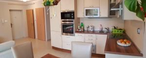 a kitchen with white cabinets and a bowl of fruit on a counter at Sweet Home Apartment in Keszthely