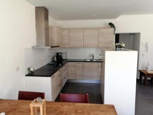 a kitchen with white cabinets and a table and chairs at Appart'hotel Durbuy in Durbuy
