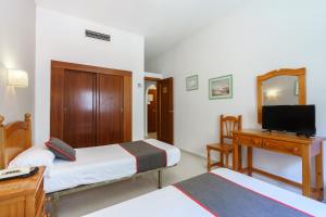 a bedroom with two beds and a desk and a television at Hotel Costa Andaluza in Motril