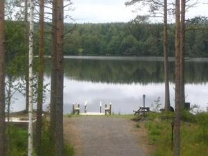 un chemin à côté d'un lac avec deux bancs dans l'établissement Holiday Home Kurrela by Interhome, à Toiviaiskylä